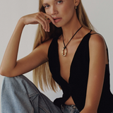 Woman wearing a black sleeveless top and denim jeans against a plain background