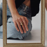 Person wearing gold rings with a framed mirror in front