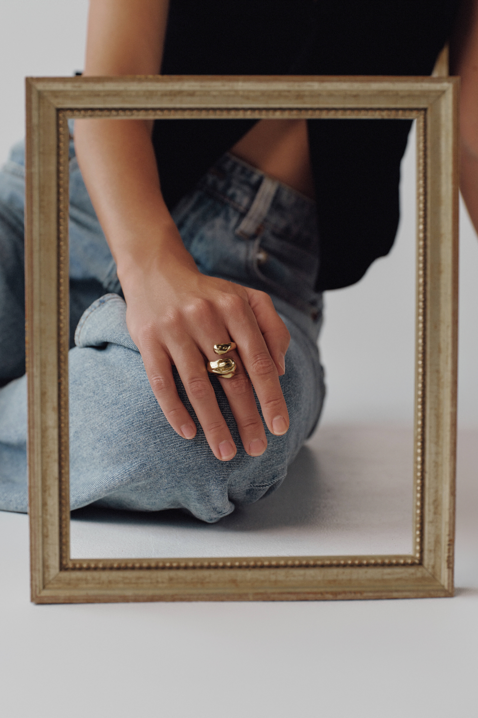 Person wearing gold rings with a framed mirror in front