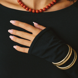 Person wearing a red beaded necklace and gold bracelets on a black background