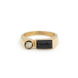 A gold ring featuring an emerald-cut center stone and a pavé band, shown on a clean white background with a soft reflection.