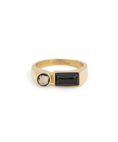 A gold ring featuring an emerald-cut center stone and a pavé band, shown on a clean white background with a soft reflection.