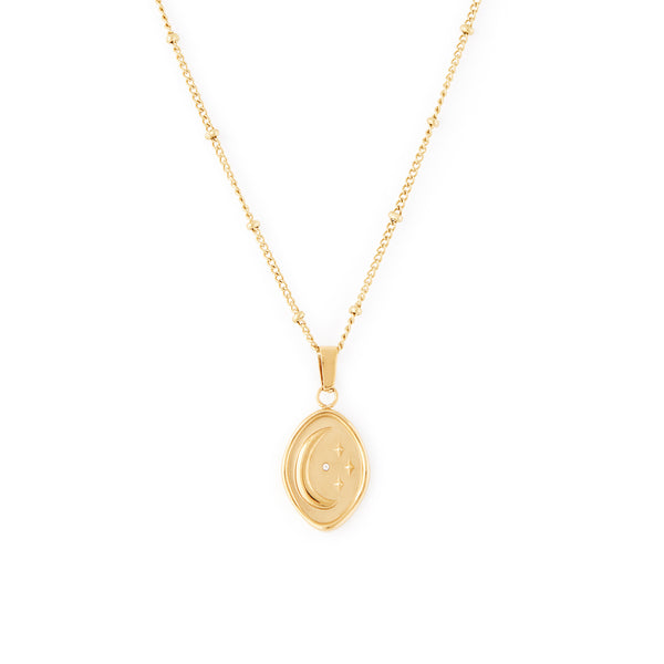 A gold-colored necklace with a beaded chain and an abstract shaped pendant featuring an embossed moon and star with a tiny cubic zirconia stone. Céleste Necklace - Gold