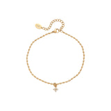 Gold anklet with a small floral charm on a white background