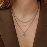 A person in a brown blazer wears three silver chain necklaces. Two are simple and elegant, while the lowest Twenty Compass Andy Necklace - Silver has a round green aventurine stone pendant, adding a subtle pop of color to the outfit.