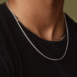 A person in a black shirt wears the Twenty Compass 2mm Rope Necklace - Silver, adding texture to their style. The background features a muted green color.