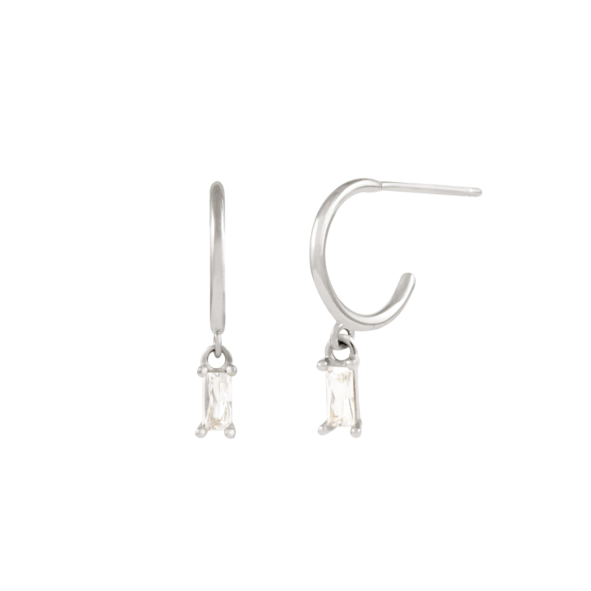 The Alaska Earrings - Silver by Twenty Compass are minimalist silver hoops with dangling rectangular clear gemstones and sparkling cubic zirconia, set against a plain white background.